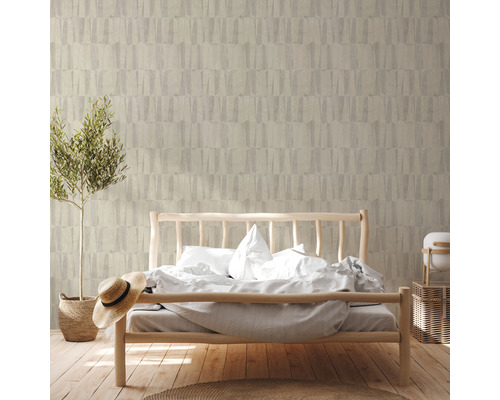 Chambre à coucher avec lit devant un mur avec du papier peint à motifs et une plante en pot.