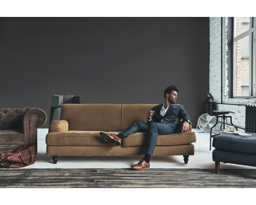 Scène de salon avec canapé, fauteuil, tabouret et homme élégamment vêtu