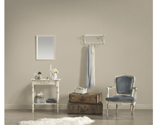 Salon décoratif avec table, miroir, bagages, chaise et porte-manteau.