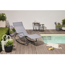 Szene mit grauer Gartenliege, zwei Beistelltischen und Pflanzen auf einer Holzterrasse neben einem Pool