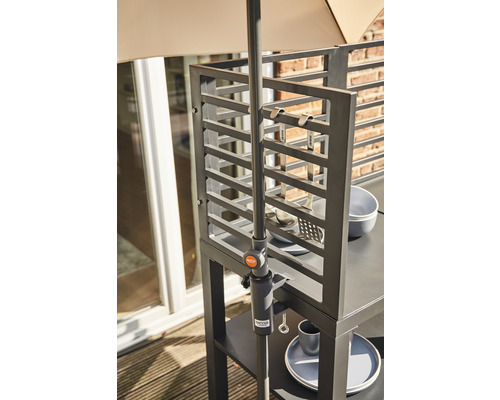 Detailansicht einer Outdoorküche mit Regalen, Kochutensilien und Sonnenschirmhalterung.