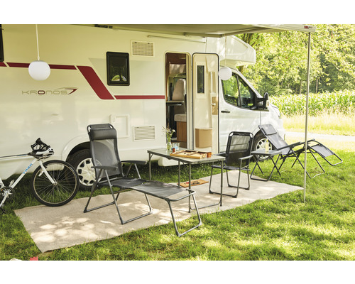 Scène de camping avec caravane, table, chaises, chaise longue et vélo