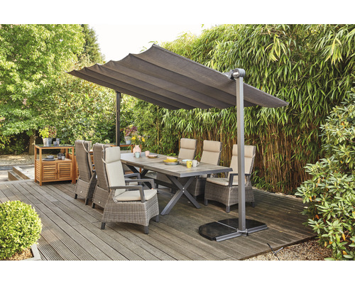 Scène de jardin avec table à manger, chaises et parasol sur une terrasse.