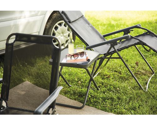 Scène de camping avec chaise longue, table d''appoint, boissons et accessoires sur une pelouse