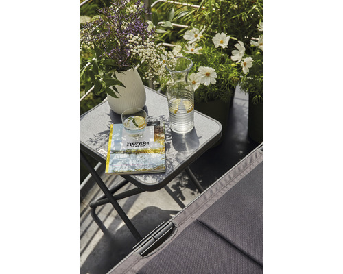 Scène sur un balcon avec une table d''appoint, une boisson et des décorations pour une ambiance détendue