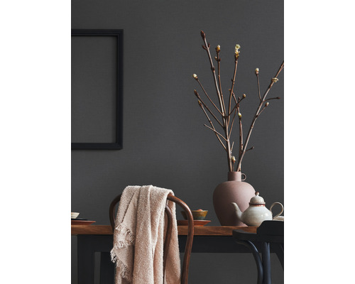 Dekoratives Interieur mit Tisch, Stuhl, Vase, Zweigen und Textilien.