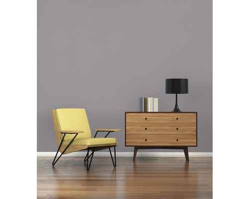 Wohnzimmer mit Sessel, Kommode, Lampe und Büchern auf Holzboden