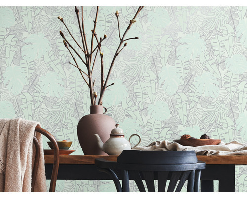Helles Zimmer mit Esstisch, Geschirr und Tapete mit Blättermuster