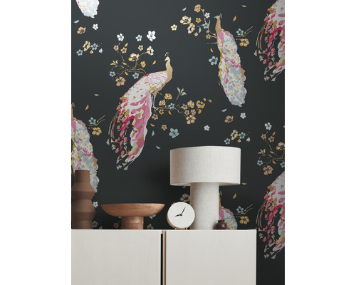 Salon avec un papier peint à motifs de paons, une lampe de table et des objets décoratifs sur un buffet.