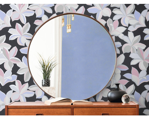 Miroir rond au-dessus d''une commode devant un papier peint floral