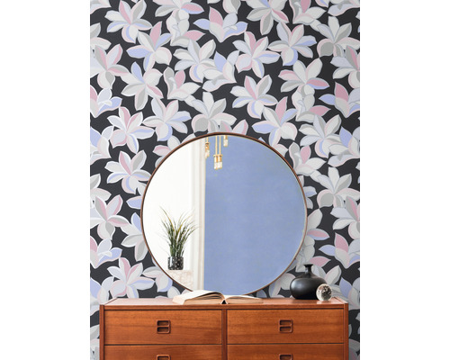 Intérieur décoratif avec une commode devant un papier peint floral et un miroir rond.