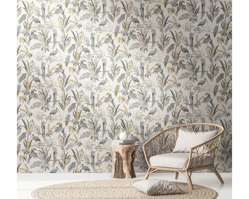 Pièce avec papier peint jungle avec oiseaux et plantes, fauteuil en rotin et table d''appoint en bois