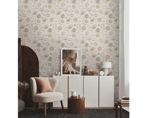 Salon lumineux avec papier peint à motifs floraux, fauteuil et commode