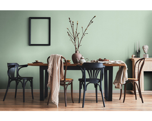 Salle à manger avec table en bois, chaises et décorations dans une pièce lumineuse.