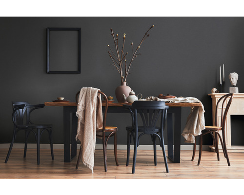 Esszimmer mit Holztisch und Stühlen vor grauer Wand