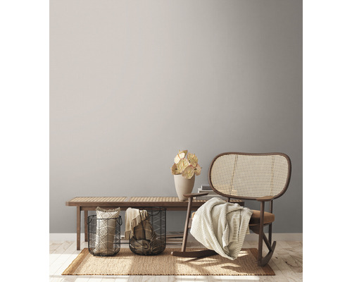 Scène de salon avec banc en bois, paniers métalliques, décorations, tapis et rocking-chair.