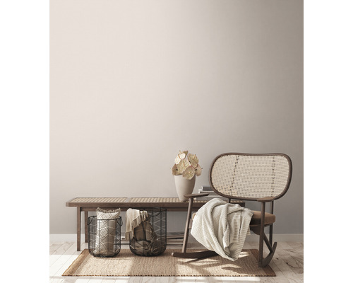 Scène de salon avec banc, fauteuil à bascule en rotin, paniers et décoration sur un tapis.