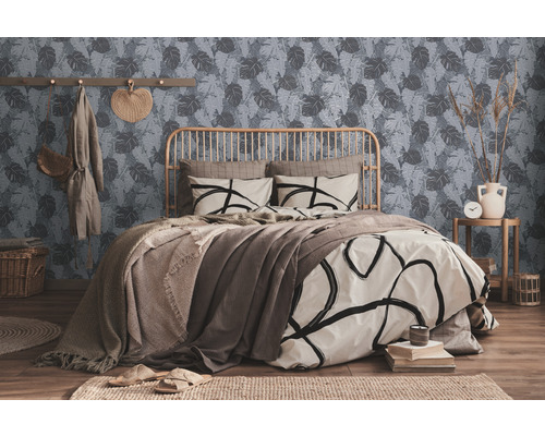 Une chambre avec un lit, un mur à motifs de feuilles et des éléments décoratifs.