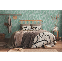 Chambre lumineuse avec lit devant un papier peint vert à motifs de feuilles