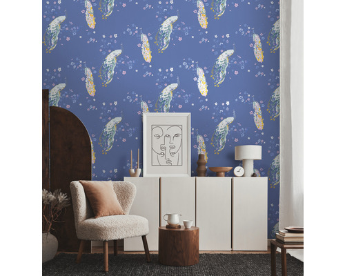 Un salon avec du papier peint à motifs floraux, un fauteuil et une armoire blanche.