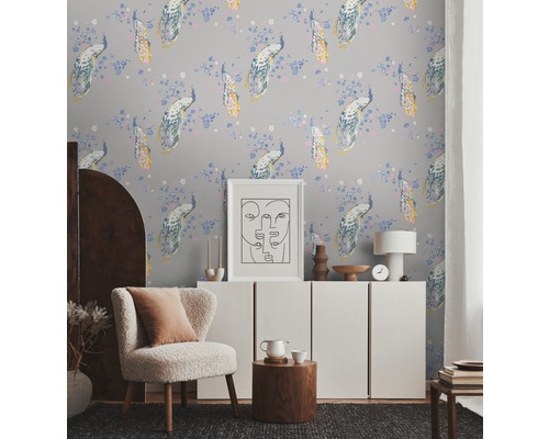 Pièce lumineuse avec papier peint à motifs de paons, fauteuil, buffet et décorations pour une ambiance chaleureuse.