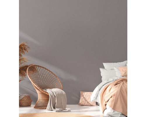 Heller Raum mit Rattansessel, Bett und Dekoration für ein gemütliches Ambiente.