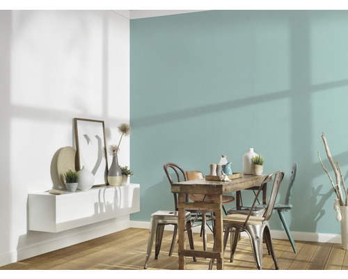 Salle à manger avec table en bois, chaises et étagère murale avec décorations devant un mur coloré