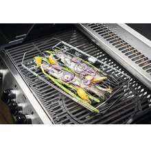 Poisson dans un panier à griller sur un gril à gaz avec citron, oignons et oignons nouveaux