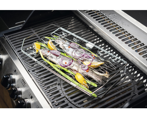 Poisson dans un panier à griller sur un gril à gaz avec citron, oignons et oignons nouveaux