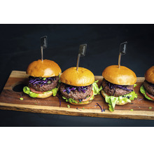 Plusieurs hamburgers avec viande, salade et drapeaux Enders sur une planche à découper en bois