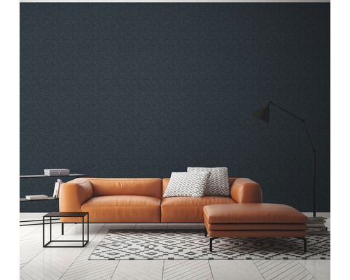 Salon avec canapé en cuir orange, tabouret, étagère, lampadaire et papier peint à motifs