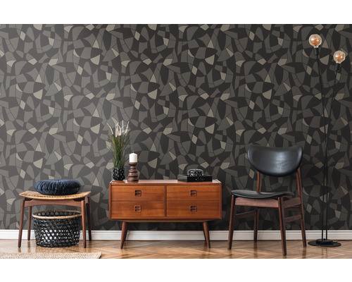 Mur décoratif avec papier peint à motifs géométriques en gris et noir, combiné avec des meubles en bois et un lampadaire.