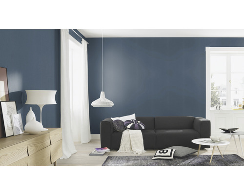 Salon avec canapé, commode, lampe et décoration devant un mur bleu foncé
