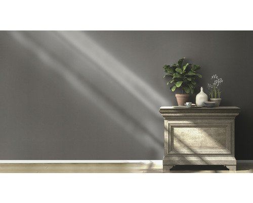 Commode décorative avec plantes et objets de décoration devant un mur gris