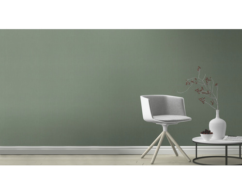 Salon avec une chaise pivotante en bois et une petite table devant un mur vert