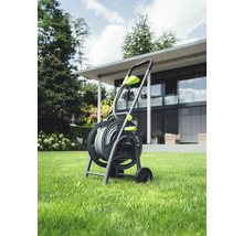 Gartenschlauchwagen mit Schlauch auf Rasenfläche vor einem Haus.