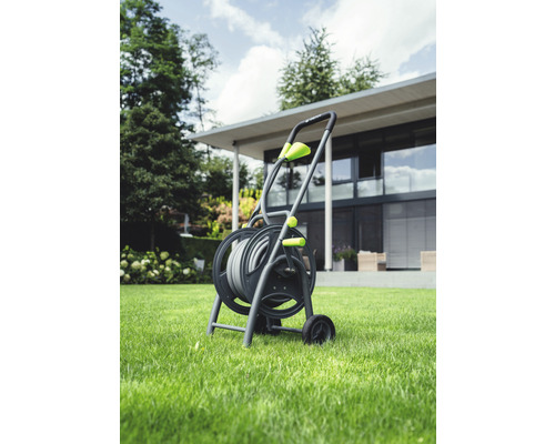 Gartenschlauchwagen mit Schlauch auf Rasenfläche vor einem Haus.