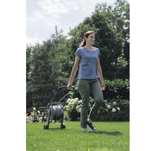 Frau zieht einen Schlauchwagen durch einen Garten