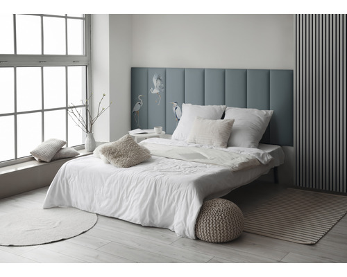 Helles Schlafzimmer mit Bett, Kissen und blauem Kopfteil mit Vogelmotiv