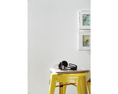 Gros plan d''un mur avec une texture de crépi, un tabouret jaune, des écouteurs et des cadres photo