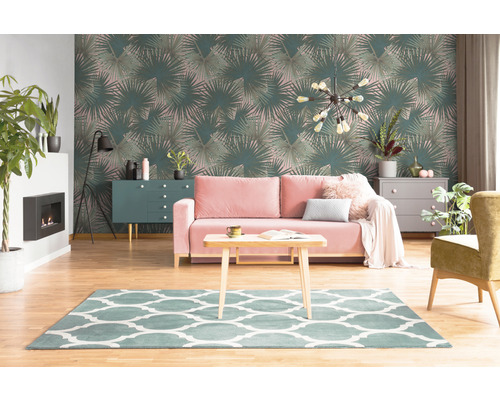 Salon avec papier peint à motif de feuilles de palmier, canapé, tapis et meubles.