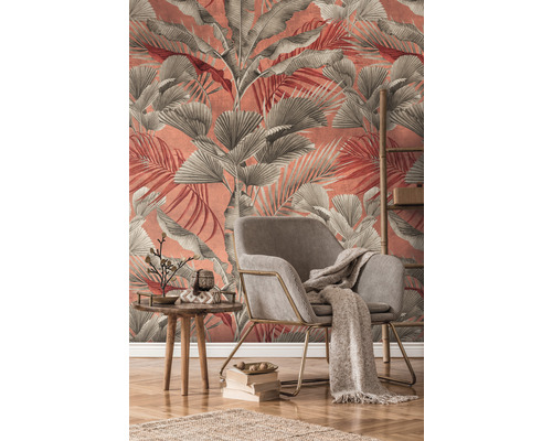 Salon avec fauteuil, table et décoration devant un mur avec papier peint à feuilles