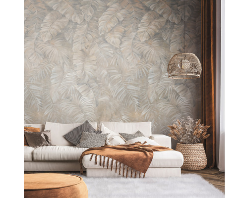 Salon avec papier peint à motifs, canapé, coussins et lampe.