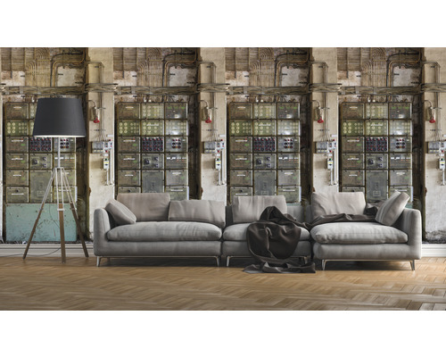 Wohnzimmer mit grauer Couch, Stehlampe und Wandtapete mit Schaltschrank-Motiv für ein industrielles Ambiente.