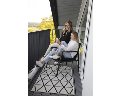Deux femmes assises sur un balcon avec un tapis géométrique.