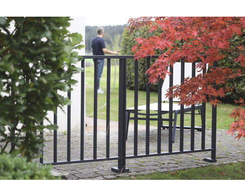 Zaunelement aus Metall im Garten mit Person im Hintergrund