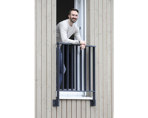 Homme debout près d''une fenêtre avec une grille de fenêtre