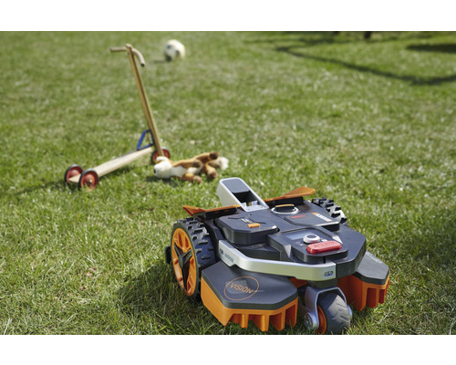 Robot tondeuse sur une pelouse avec des jouets en arrière-plan