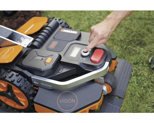 Gros plan d''un robot tondeuse en marche avec un doigt sur le bouton de démarrage