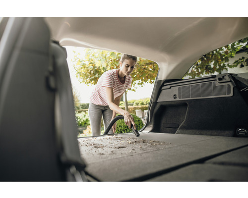 Femme passe l''aspirateur dans le coffre d''une voiture